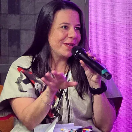 Ana Karine Menezes falando ao microfone durante uma vivência da Encantaria
