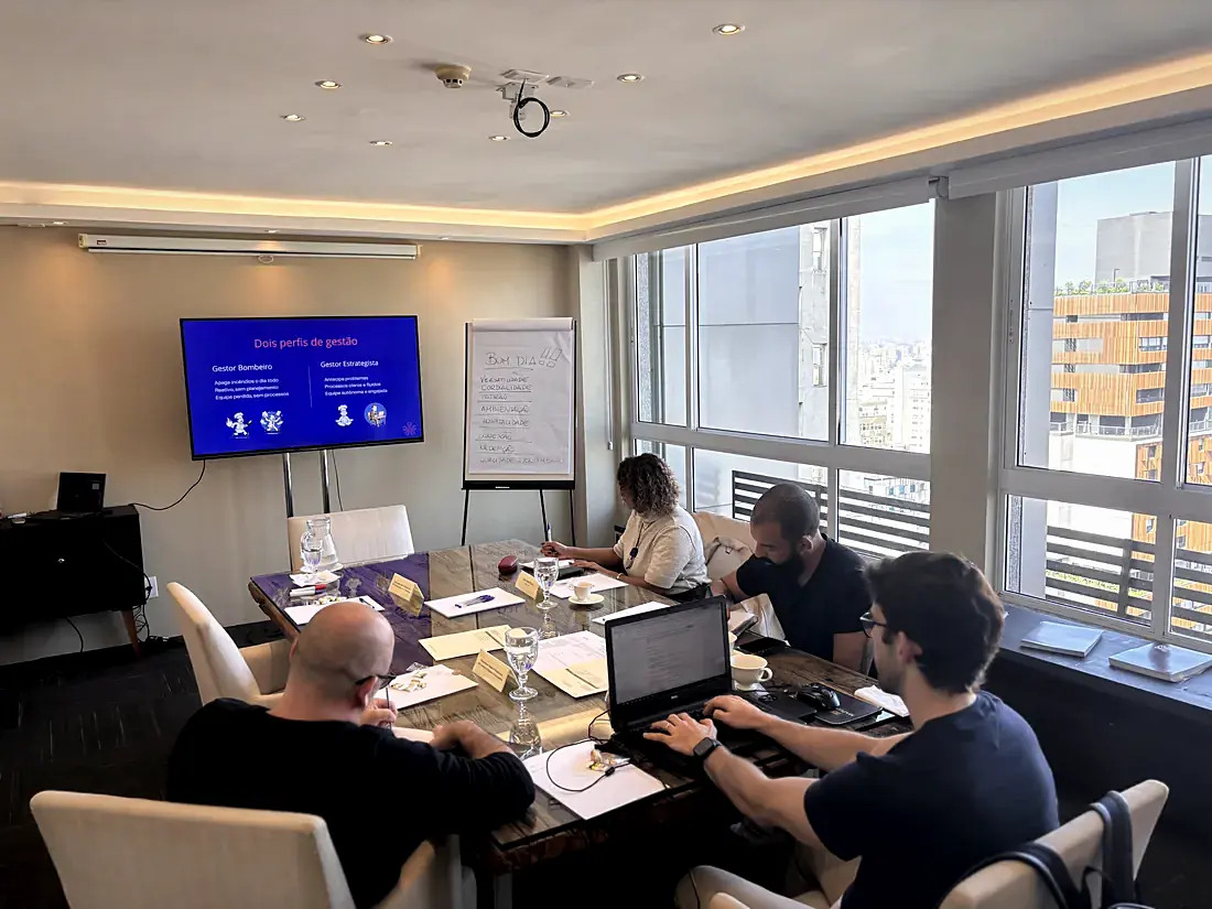 Treinamento em sala de reunião, com slide sobre perfis de gestão na tela